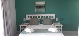 杰弗里湾OCEAN VIEW GUEST HOUSE的蓝色卧室,配有带毛巾的床