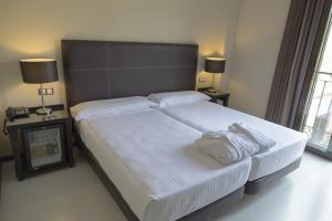 特里略Hotel Real Balneario Carlos III的卧室配有一张带白色床单和枕头的大床。