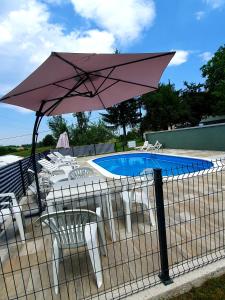 斯莫利亚纳茨米里亚娜宾馆的粉红色的遮阳伞和椅子以及游泳池