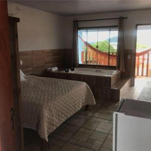 皮雷诺波利斯Pousada Estrela Guia的卧室配有床、浴缸和窗户。