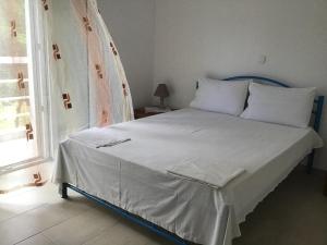 KamariotissaVilla Maria的一间卧室配有一张带白色床单的床和一扇窗户。