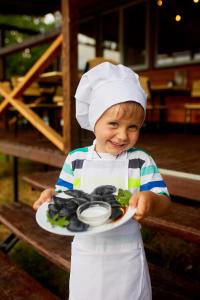 GrushevtsyКаньон的戴着厨师帽的年轻男孩,拿着一盘食物