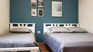 诺维萨德Lovely Private Flats FREE parking的蓝色墙壁客房的两张床