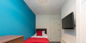 克鲁Townhouse @ Edleston Road Crewe的一间卧室设有蓝色的墙壁和一张带红色枕头的床