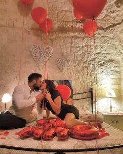 阿尔贝罗贝洛I Trulli Di Nonno Giovanni的男人和女人坐在床上,用红色气球