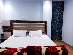 坎普尔Kartar Yatri Niwas的卧室配有一张大白色床,地板上摆放着红色鲜花