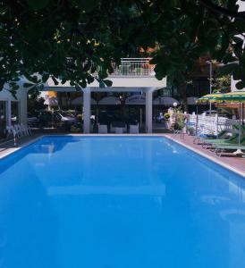 里米尼苏西酒店的大楼前的大型蓝色游泳池