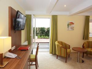 林茨阿德勒戈尔登酒店的酒店客房配有书桌和带电视的桌子。