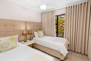 德班14 The Shades - by Stay in Umhlanga的一间卧室设有两张床和窗户。