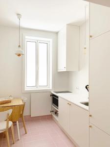 波尔图Guest House Arca d´'Água的厨房配有白色橱柜、桌子和窗户。