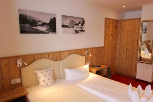 洛伊塔施迪罗勒霍夫酒店的卧室配有白色的木墙床