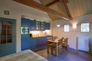 奥斯楚特Huys en Hoff Aen Den Haspel的厨房配有蓝色橱柜和桌椅