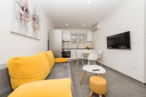 马卡尔斯卡Apartments PETRUSIC的客厅配有黄色的沙发和桌子