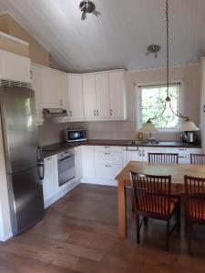 韦斯特罗斯The Cottage Badelunda的厨房配有桌子和不锈钢冰箱。