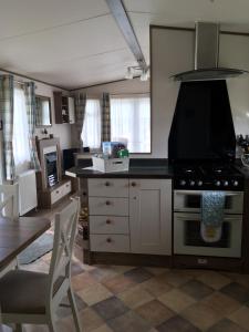 纽基BRANWOOD Acorn Caravan Holidays Newquay的厨房配有炉灶和桌子。