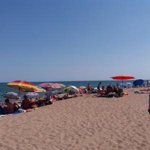 切尔诺莫斯克Caramel'的一群人坐在海滩上,拿着遮阳伞