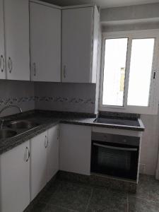 阿尔么丽亚COSTA DE ALMERIA PLAYA的厨房配有白色橱柜、水槽和窗户。