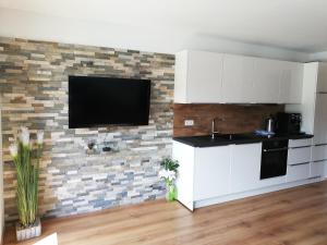 圣迈克尔隆高Sonnen-Appartement Heidi的厨房配有白色橱柜和砖墙上的电视