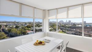 布里斯班Oaks Brisbane Woolloongabba Suites的白色的客房设有窗户和白色的桌椅。