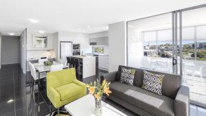 布里斯班Oaks Brisbane Woolloongabba Suites的客厅以及带沙发和桌子的厨房。