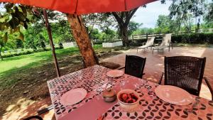 罗勇Kampu Nature Pool Villa Rayong的一张带红色雨伞的桌子和一张带食物的桌子