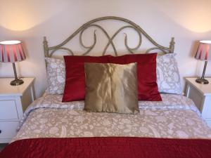 伍斯特Shrubbery Guest House的一间卧室配有一张带红色枕头的床和两盏灯。