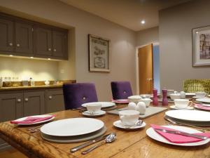 HildenboroughThe Barn At Woodview的餐桌,配有白色的盘子和紫色的椅子