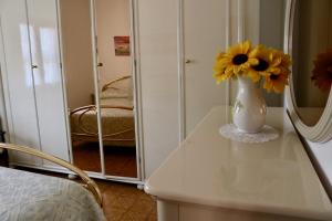 马奥莱Il rifugio di Elena的镜子前的桌子上装着黄色花卉的花瓶