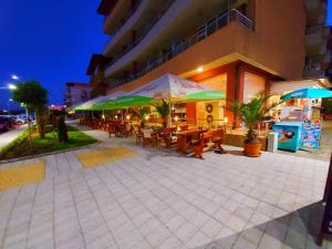 普里莫尔斯科Hotel Ancora Beach的大楼前的餐厅,配有桌子和遮阳伞