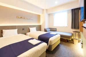 东京hotel MONday Premium Ueno Okachimachi的酒店客房设有两张床和窗户。