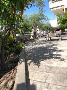 尼亚普拉莫斯Glykanisos Suites的公园里两长椅和树木的路边