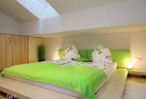 滨湖采尔Chalet Der Bichlhof的卧室配有一张带绿床单和枕头的大床。