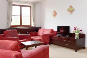 塔查斯卡-鲁穆尼卡Hotel Tulipan的客厅配有红色椅子和电视