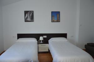 ReílloRural Reillo Alojamientos Rurales的墙上有两张照片的房间的两张床