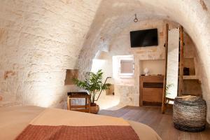 阿尔贝罗贝洛Monte Adamello - dimora nei trulli的一间卧室设有一张床,并在石墙内配有电视。