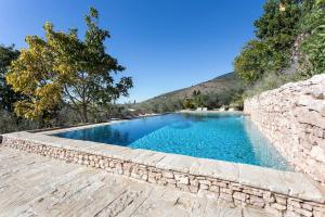 PoretaVilla della Genga Country Houses的一座游泳池,其石墙旁边设有一座石墙