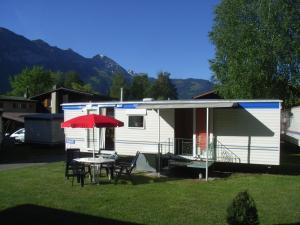 因特拉肯庄园农场阿尔托金瑞士度假屋5号的拖车,配有桌椅和红色雨伞