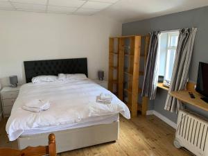福里斯The Carisbrooke的一间卧室配有一张带白色床单的床和电视。