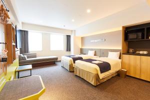 东京hotel MONday Akihabara Asakusabashi的酒店客房,设有两张床和一张沙发