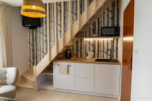 达布基Domki Letniskowe AlexJan的厨房配有白色橱柜和木楼梯箱