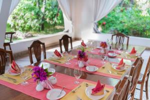 马林迪Hotel Villa Malindi的用餐室配有带粉红色餐巾的长桌