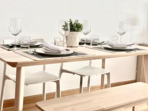 莱昂Apartamento La Sal的木桌,带玻璃杯和盘子及椅子