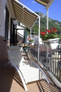 维耶特里Casa Nanà Amalfi Coast的阳台上的白色椅子,配有桌子和鲜花