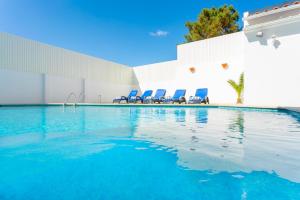 沙尔内卡Villa Sol e Mar的一座带蓝色椅子的游泳池,位于大楼旁