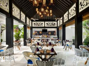 塞米亚克Avani Seminyak Bali Resort的一间带桌椅的餐厅和一间酒吧