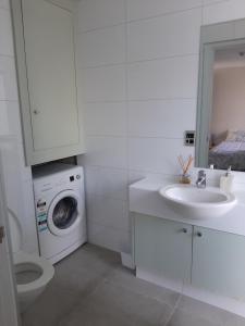 基督城City Apartment的白色的浴室设有洗衣机和水槽。