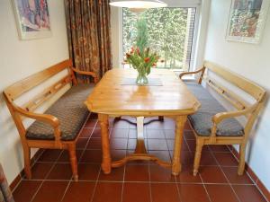 布劳沃斯港Holiday Home Den Osse by Interhome的一张木桌,上面有两把长凳和花瓶