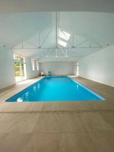 Cérans-Foulletourte多曼德贝莱酒店的一个带蓝色游泳池的大型室内游泳池