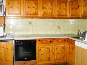 卡普尔Apartment Garni Regina - KPL642 by Interhome的厨房配有木制橱柜和黑色洗碗机。