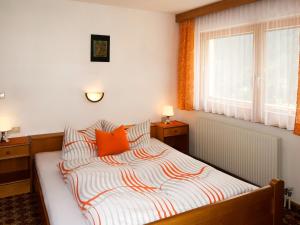 卡普尔Apartment Garni Regina - KPL642 by Interhome的一间卧室配有带橙色枕头的床和窗户。